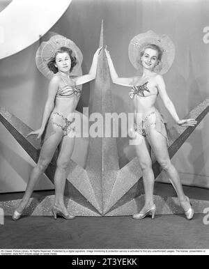 In the 1940s. Two young women from the theater ensemble from Södra teatern in Stockholm are dressed in their stage clothes, not unlike the appearance of a bikini, on the stage next to a star that was placed there as a decoration during the revue performance. Sweden 1945. Kristoffersson ref 89A-11 Stock Photo