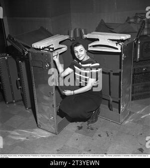 In the 1940s. A young woman photographed sitting inside a large suitcase which is open to reveal the inside. Inside the trunk, the clothes were hung neatly on hangers so that the clothes would be organized and avoid getting wrinkled when the trunk was transported. Around the larger trunk are smaller suitcases of various sizes. Sweden 1945. Kristoffersson ref R127-4 Stock Photo