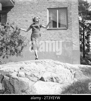 1950s woman. A young blonde woman is seen jumping of joy outside a building on a sunny day.  Sweden 1953. Photo Kristoffersson Ref BL96-4 Stock Photo