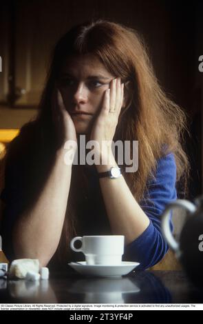 A woman sits in a cafe and rests her head in her hands, looking serious. Sweden 1982 Stock Photo