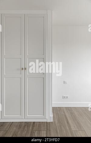 Empty room with built-in wardrobes with white wooden doors Stock Photo