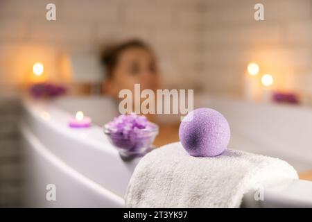 home spa. woman relaxing in bathtub in candle light and using bath bomb and sea salt crystals for body skin moisturizing Stock Photo