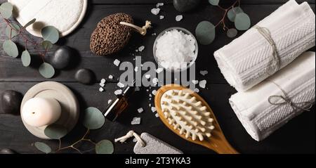 spa treatment. skin care items for bath procedures on dark black wooden table. body wellness. top view banner Stock Photo
