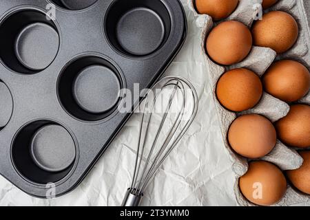 Form for baking cupcakes eggs in a box and whisk on white background Stock Photo
