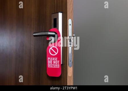 Wooden Door of hotel room with red sign please do not disturb Stock Photo