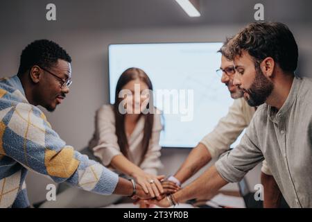 Business Professionals Collaborating on Architectural Plans in Meeting Room. Successful Team Putting Hands Together. Stock Photo