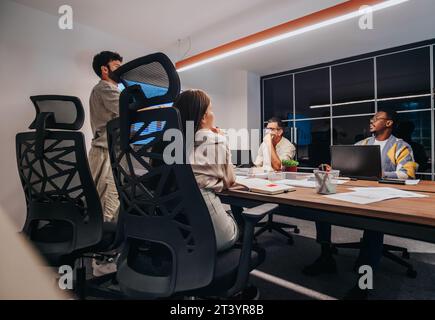 Multiracial Team of Architects and Engineers Discussing Blueprint in a Collaborative Business Meeting Stock Photo