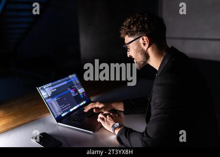 Young man mobile developer writes program code on a computer, programmer work in home office. Stock Photo