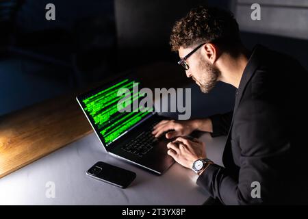 Young man mobile developer writes program code on a computer, programmer work in home office. Stock Photo