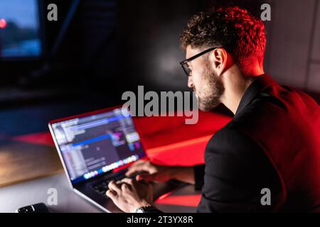 Young man mobile developer writes program code on a computer, programmer work in home office. Stock Photo