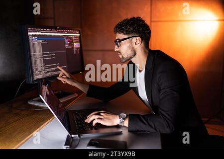 Young man mobile developer writes program code on a computer, programmer work in home office. Stock Photo