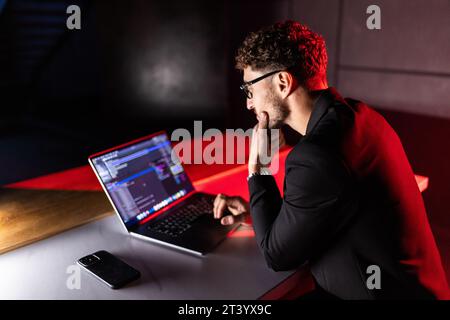 Young man mobile developer writes program code on a computer, programmer work in home office. Stock Photo