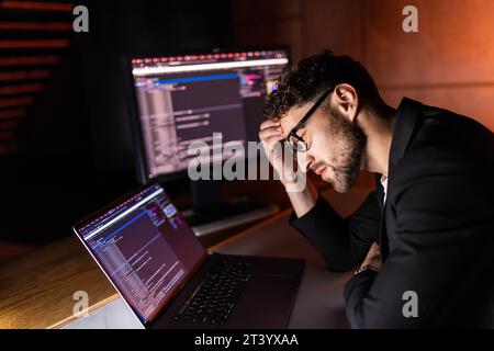 Young man mobile developer writes program code on a computer, programmer work in home office. Stock Photo