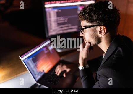 Young man mobile developer writes program code on a computer, programmer work in home office. Stock Photo