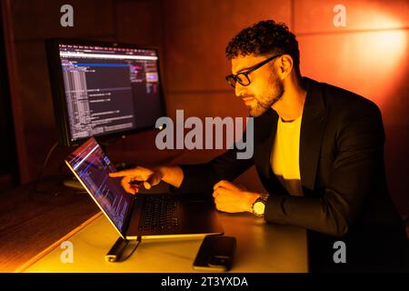 Wanted hackers coding virus ransomware using laptops and computers. Stock Photo