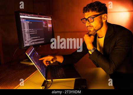 Wanted hackers coding virus ransomware using laptops and computers. Stock Photo