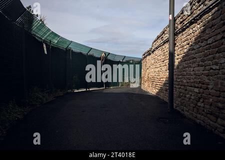 Bend  in a gravel path between a fence and a brick wall on a cloudy day Stock Photo