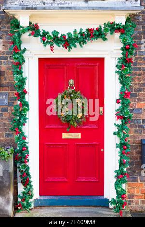 BUCKINGHAMSHIRE, UK - December 26, 2022. Christmas wreath and garland on traditional front door painted red, UK Stock Photo