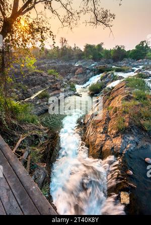 At sunset.Sunlight shining on rocks,next to blurred movement of water,rushing by,at the main waterfalls and rapids of Don Khon island. Stock Photo
