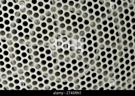 Geometric pattern of holes on the metal grate. Abstract detail photography of perforation on back side of hairdryer. Stock Photo