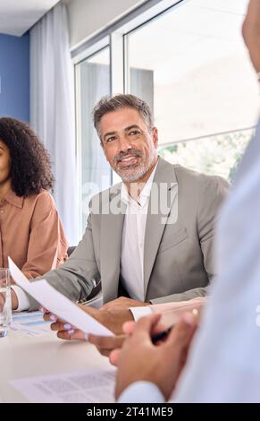 Smiling older businessman holding document communicating at group meeting. Stock Photo