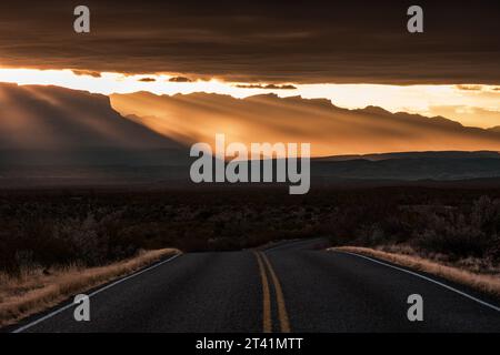 Road Bends Over Hill Below Dramatic Sun Rise Rays in Big Bend Stock Photo