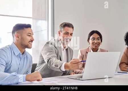 Old executive manager teaching workers using laptop at office business meeting. Stock Photo