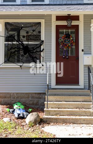 close-up view of a brown door on a gray and white house with Halloween decorations, in daytime sunlight. Stock Photo