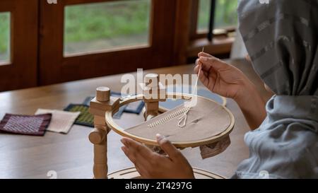 Artistry Unveiled: Women's Hand Stitching Border Pattern on Linen Fabric Stock Photo