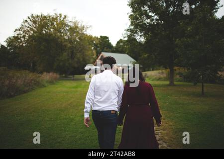 An intimate moment between a loving couple as they stroll through a lush, grassy field Stock Photo