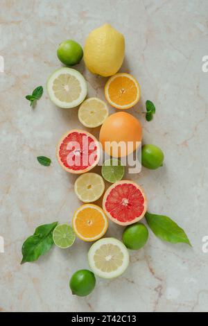 A vibrant assortment of citrus fruits, including oranges, lemons, and limes, arranged in a bright yellow bowl on a flat surface Stock Photo
