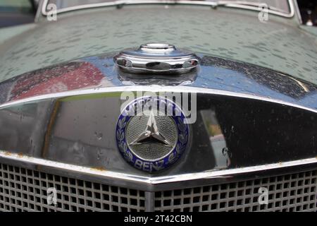 A close-up shot of the hood of a classic Mercedes-Benz automobile, showcasing the iconic logo of the brand Stock Photo
