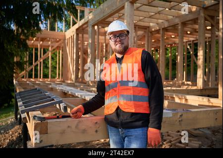 Two men in hard hats and safety vests working on a piece of wood