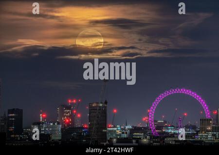 London, UK. 28th October 2023. UK Weather: Hunter's Moon sets over London Eye. A 98.9% Waxing Gibbous near full-moon sets at 6:50am on Saturday morning . The name 'Hunter's Moon' is believed to originate as a call for hunters to venture out and hunt in preparation for the colder months ahead. Credit: Guy Corbishley/Alamy Live News Stock Photo