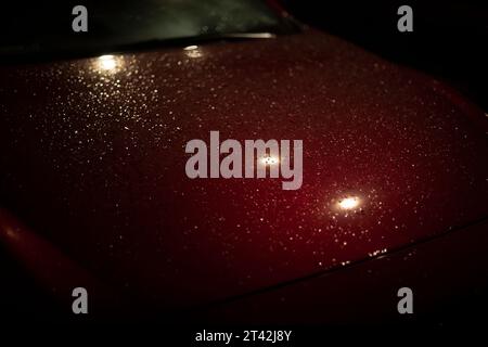 Wet car in parking lot. Drops on hood of car. Parking in detail at night. Wet surface. Stock Photo