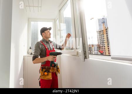 Construction worker repairing plastic window with screwdriver indoors Stock Photo