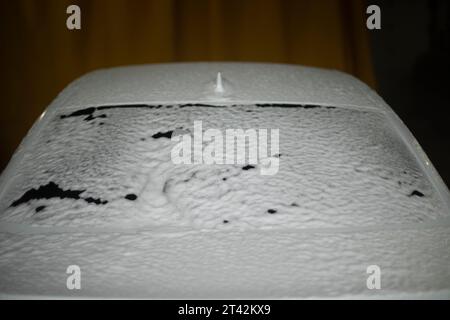 Machine in soap suds. Car wash in city. Cleaning car from dirt. White foam on transport. Stock Photo