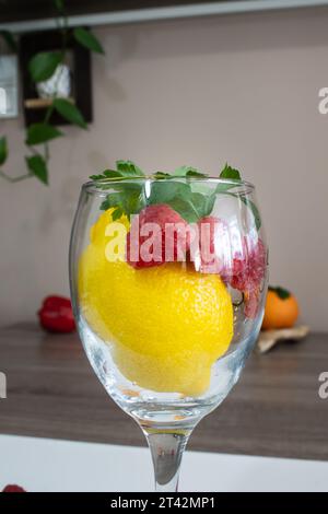 The fresh lemons and raspberries placed in a clear glass Stock Photo