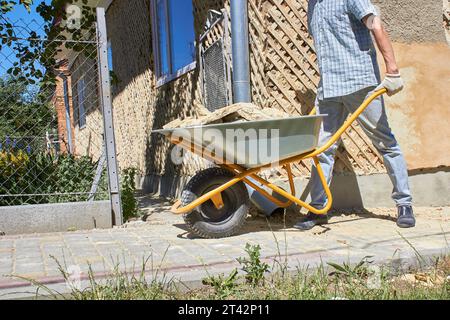 work on the construction of the wheelbarrow removal of an old plaster Stock Photo