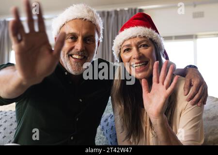Happy senior caucasian couple sitting on sofa having christmas video call at home Stock Photo