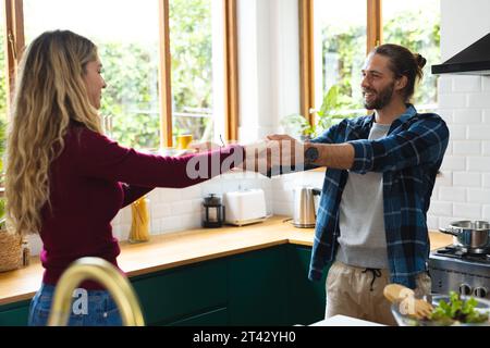 Romantic caucasian couple preparing food, having fun dancing in kitchen Stock Photo