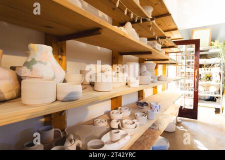 Pottery bowls, vases and plates on shelves in pottery shop Stock Photo