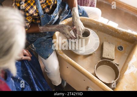African american potter working on clay vase using potter's wheel in pottery studio Stock Photo
