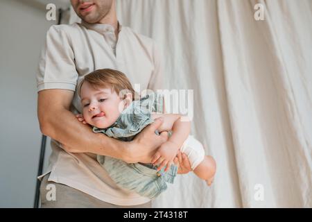 Father standing in a living room rocking his daughter in his arms Stock Photo