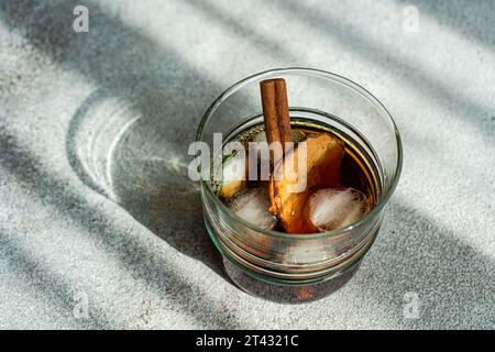 Apple cider cocktail with dried apple slices and a cinnamon stick on a table Stock Photo