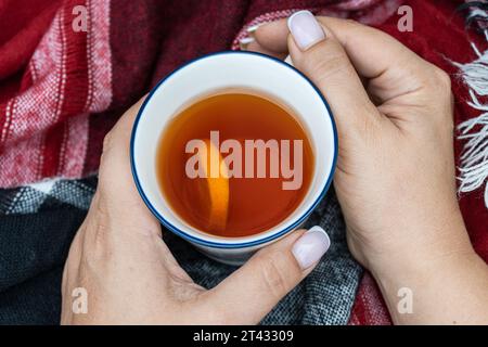 Overhead view of a woman holding a cup of black tea with lemon Stock Photo