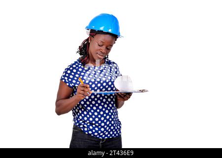 young female construction engineer wearing blue hard hat and reading notes on clipboard. Stock Photo