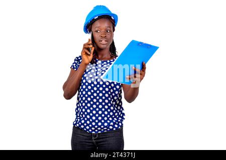young female construction engineer holding clipboard and talking on mobile phone. Stock Photo