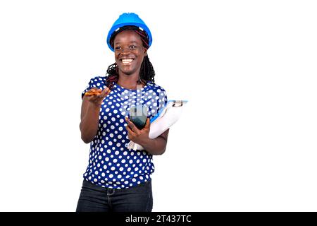 beautiful young female construction engineer holding mobile phone and clipboard while smiling. Stock Photo
