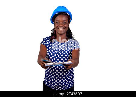 beautiful young female construction engineer wearing hard hat and giving clipboard while smiling. Stock Photo